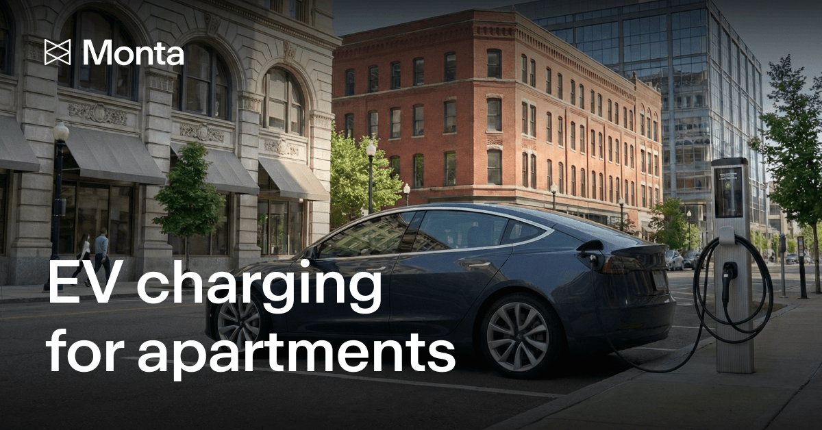 A sleek electric vehicle charging at a station outside modern apartment buildings, with trees lining the street.