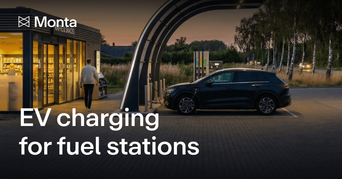 A sleek electric vehicle charges at a modern station as a person walks towards a building, set against a twilight landscape.