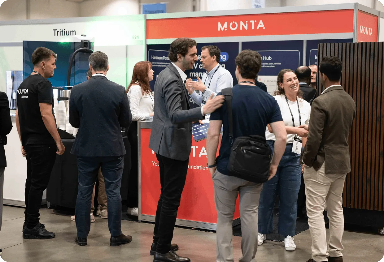 Monta's booth at a conference, featuring a red backdrop with the word